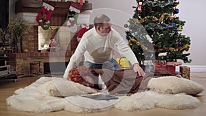 Wide shot of loving caring husband covering wife with blanket. relaxed Caucasian woman sleeping at Christmas tree at