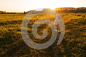 Wide shot of loving young couple in relationship hugging and kissing enjoying each other in wonderful sunlight of sunset