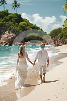 Wide shot of newly wed couple walking on the sandy tropical beach