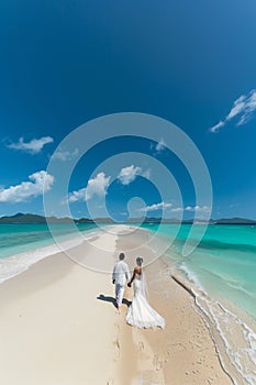 Wide shot of newly wed couple walking on the sandy tropical beach