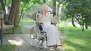 Wide shot portrait of cheerful disabled Caucasian woman in wheelchair waving at tablet selfie camera and talking