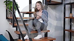 Wide shot portrait of happy teenage girl reading hugging book looking away dreaming. Caucasian pretty teenager enjoying