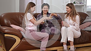 Wide shot relaxed Asian and Caucasian women with cappuccino sitting on couch as friend entering living room with crepes