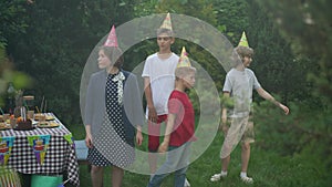 Wide shot relaxed children dancing in sunbeam in slow motion on backyard celebrating birthday. Happy carefree Caucasian