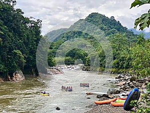 Wide shot of river and tropical mountains in Ecuador with rafting groups coming ashore.