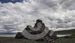 Wide shot of a rock formation by a lake with a sky full of clouds