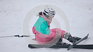 Wide shot of sad young Caucasian woman sitting on snow with injured leg. Unhappy beautiful female skier with pain in