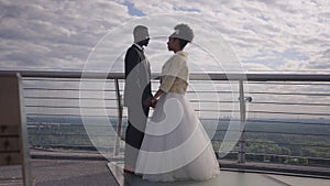 Wide shot side view of smiling loving African American bride and groom holding hands talking telling wedding vows on