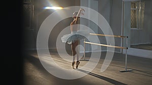 Wide shot of slim graceful ballerina rehearsing spinning on tiptoes in dancing studio spotlight. Elegant charming