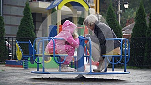 Wide shot smiling cheerful beautiful grandmother and granddaughter sitting on playground gossiping. Happy Caucasian