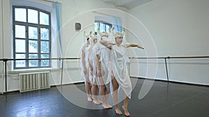 Wide shot of talented slim beautiful women rehearsing dance imitating snake in white angel costumes. Gorgeous confident