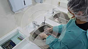 Wide shot of Technician wash dental tool under a stream of distilled water