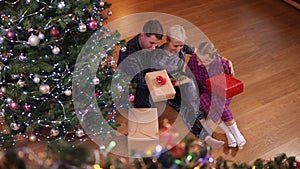 Wide shot top view of confident happy Caucasian father mother and teenage daughter sitting with Christmas presents at