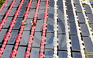 Wide shot and top view of two technician workers check and maintenance solar cell panel over the water reservoir as solar farm