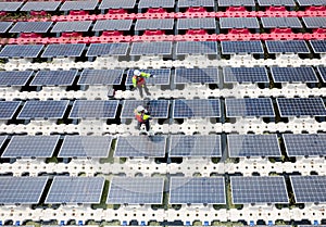 Wide shot of top view two technician workers stand and check to maintenance solar cell panels over the water reservoir as solar