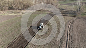 Wide shot of tractor furrowing soil and riding to camera. Agricultural machinery working on fertile field outdoors on