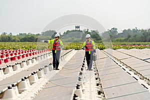Wide shot of two professional workers walk along footpath in area of base of solar cell panels network