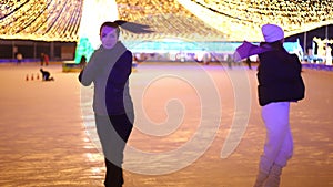 Wide shot two professional young women spinning on ice skates simultaneously in slow motion. Portrait of confident