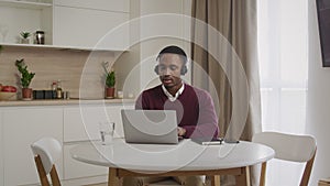 Wide shot of a young african american man in headphones working on a laptop. Close up of a call center emloyee working