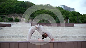 Wide shot of young flexible woman performing bending body backward exercises, various gymnastic and yoga exercises