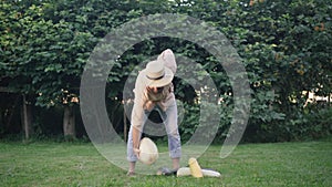 Wide shot of young man having back pain raising big zucchini standing on green meadow outdoors. Portrait of bearded