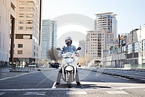 Wide shot of a young motorcyclist stopped at a traffic light in Barcelona. The man riding his scooter through photo