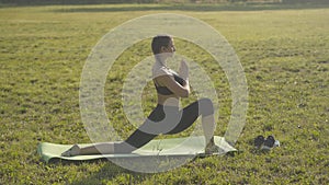 Wide shot of young slim woman with tattoo on leg practicing yoga outdoors. Side view of confident Caucasian yogi