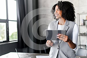With a wide smile, an African-American businesswoman interacts with her digital tablet