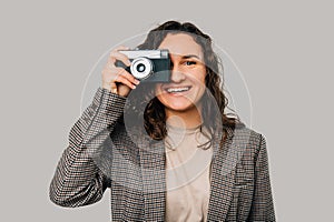 Wide smiling young woman is taking a picture with her old vintage camera.
