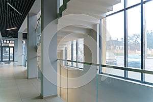 A wide staircase along the large windows in an office building. Modern interior of the lobby of an office building with large