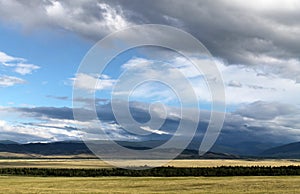 Wide steppe with yellow grass under a blue sky with white clouds Sayan mountains Siberia Russia