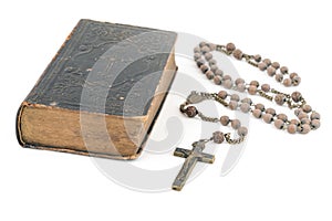 Wide studio shot of very old, vintage Holy Bible with lots of ornaments on the cover and yellow pages and old rosary