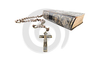 Wide studio shot of very old, vintage Holy Bible with lots of ornaments on the cover and yellow pages and old rosary