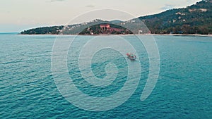 Wide top view fishing boat recedes into ocean in Colombia. Wide shot of beckoning Colombia's ocean and breathtaking