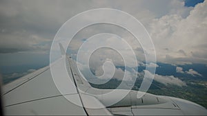 Wide view of Aircraft Wing of flying in clouds airplane as seen by passenger through porthole windows.