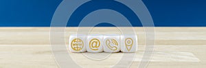 Wide view of customer service image with white dices with gold contact information and location icons on them.