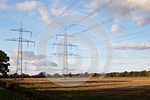 Wide view on electricity pylons under a blue sky and white clouds on a mowed field in geeste emsland germany