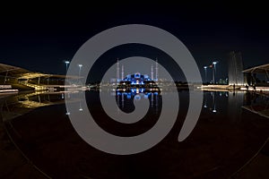 Wide view of Famous Grand Mosque in Abu Dhabi, United Arab Emirates at night with a reflection in the pool