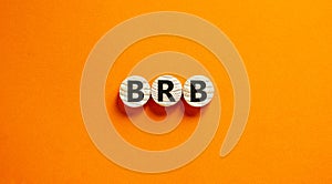 Wide view image of BRB abbreviation spelled on wooden circles. Placed over beautiful orange background, copy space. Business
