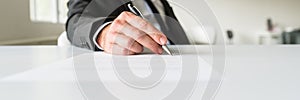 Wide view image of businessman sitting at his office desk signing a document