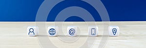 Wide view image of customer service image with five white dices with www, contact information and location icons on them