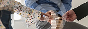 Wide view image of three business people making a tower of wooden pegs