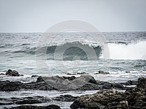 Wide view over lava rocks and arriving at the waves