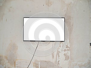A wide white screen plasma TV in a black frame hangs on an old concrete wall.