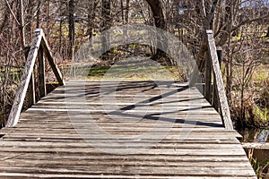 Wide wooden bridge on grass path in Buttonwood Park