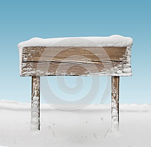 Wide wooden signpost with snow and blue sky