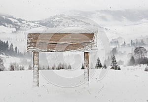 Wide wooden signpost with snow and mountains