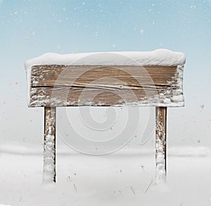 Wide wooden signpost with snow on it and snowfall