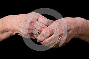 Widows hands clasped in grief on a black background.