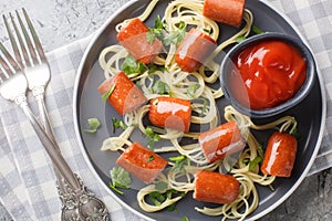 Wiener and Noodle Spider Snacks with ketchup close-up in a plate. Horizontal top view